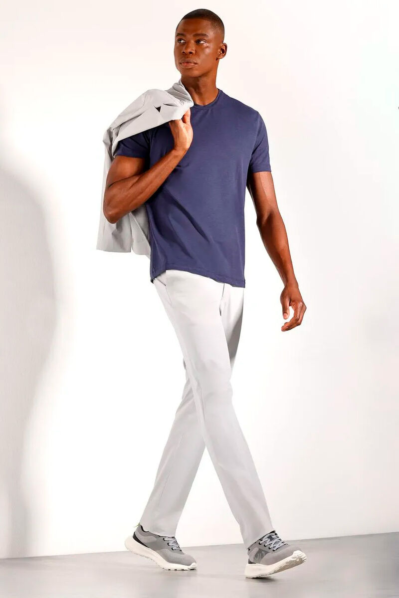 modelo usando calça de alfaiataria cinza, camiseta e tenis cinza em um fundo branco