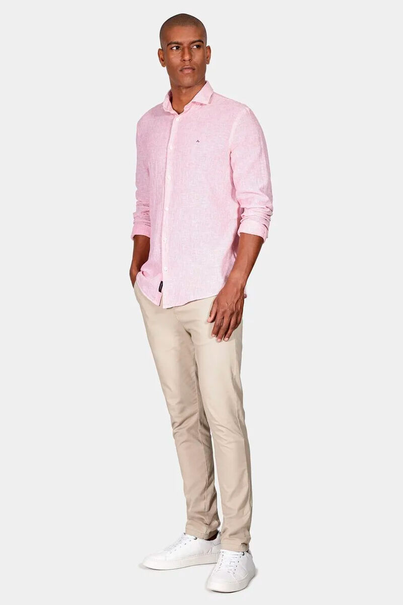 modelo usando uma camisa rosa de botão e uma calça bege em alfaiataria em um fundo branco 