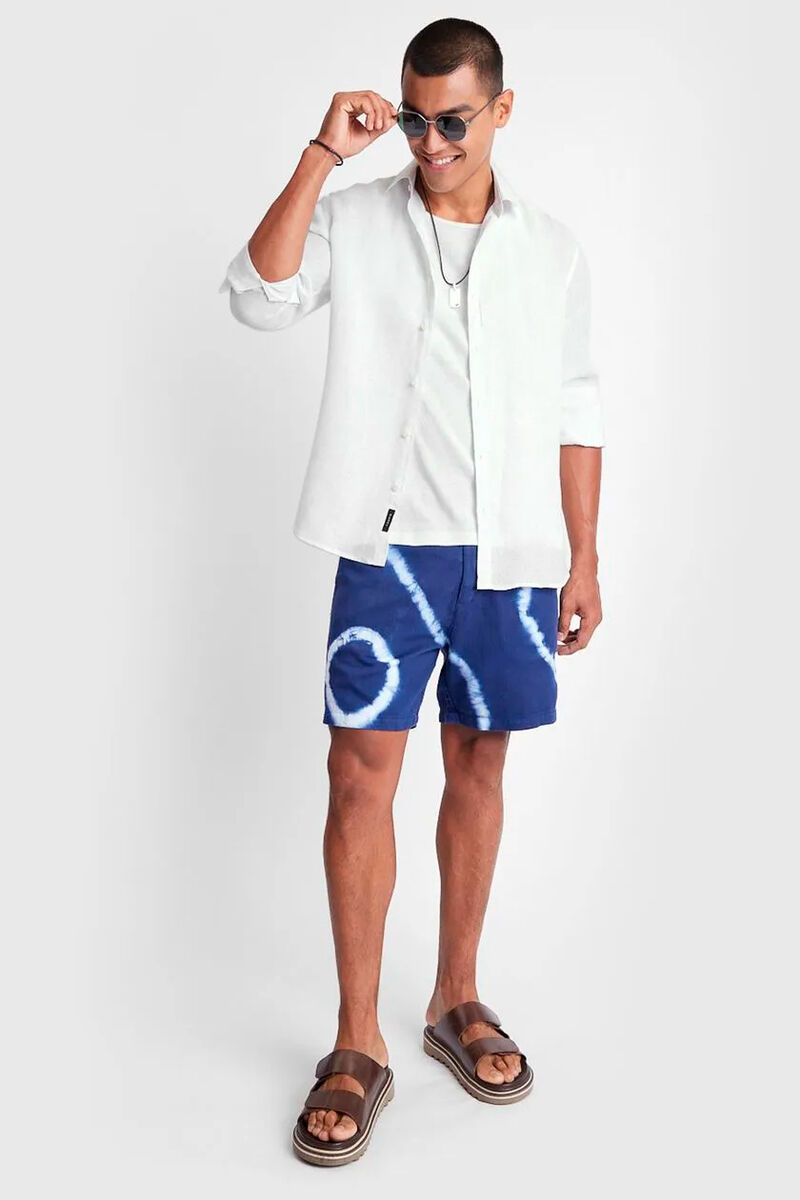 modelo usando uma camiseta branca e camisa branca junto de uma bermuda azul com listras