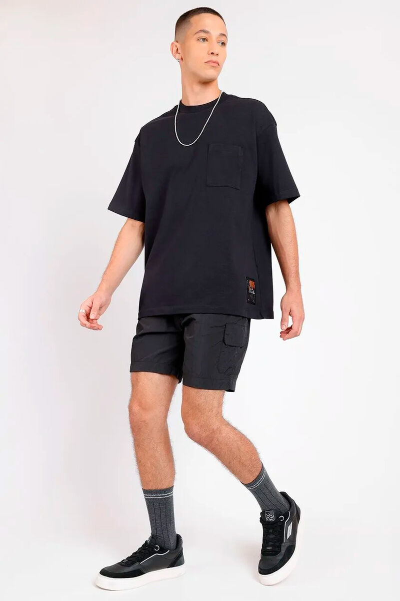 modelo usando uma camiseta preta oversized e uma bermuda preta em um fundo branco