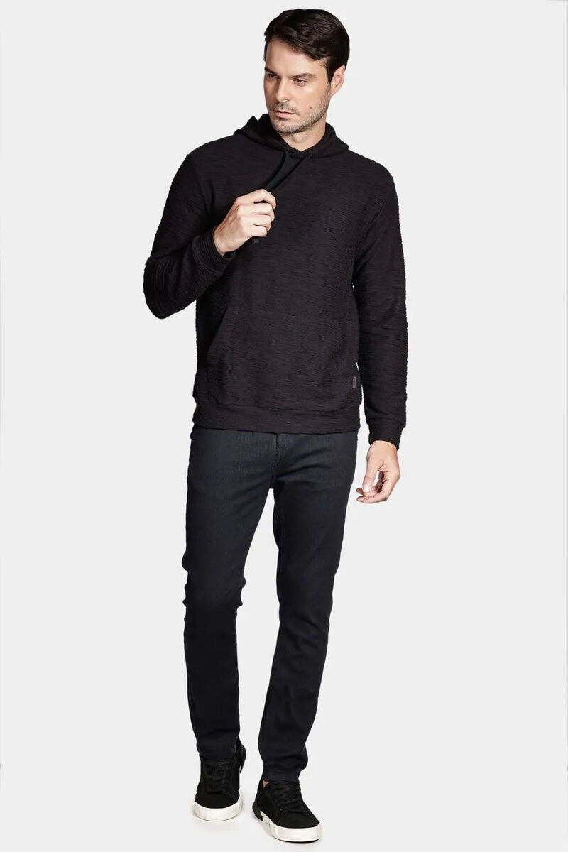 modelo usando um moletom preto e calça jeans em um fundo branco