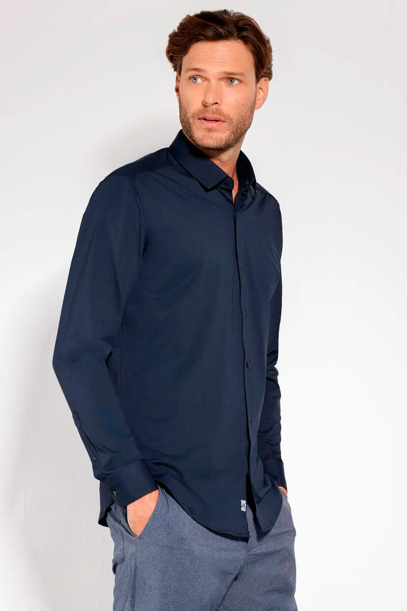 modelo usando uma camisa de manga longa azul escuro e uma calça alfaiataria cinza em um fundo branco 