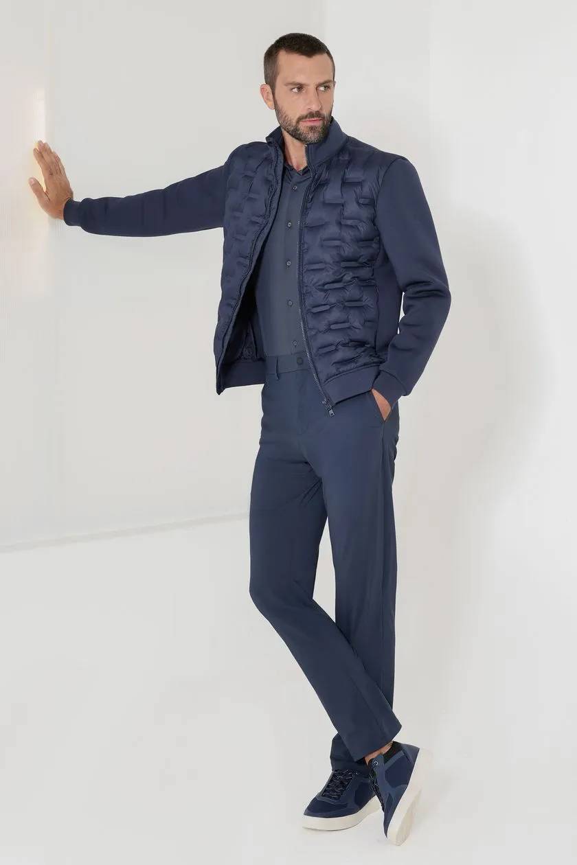 modelo de jaqueta puffer e calça jeans encostado na parede branca