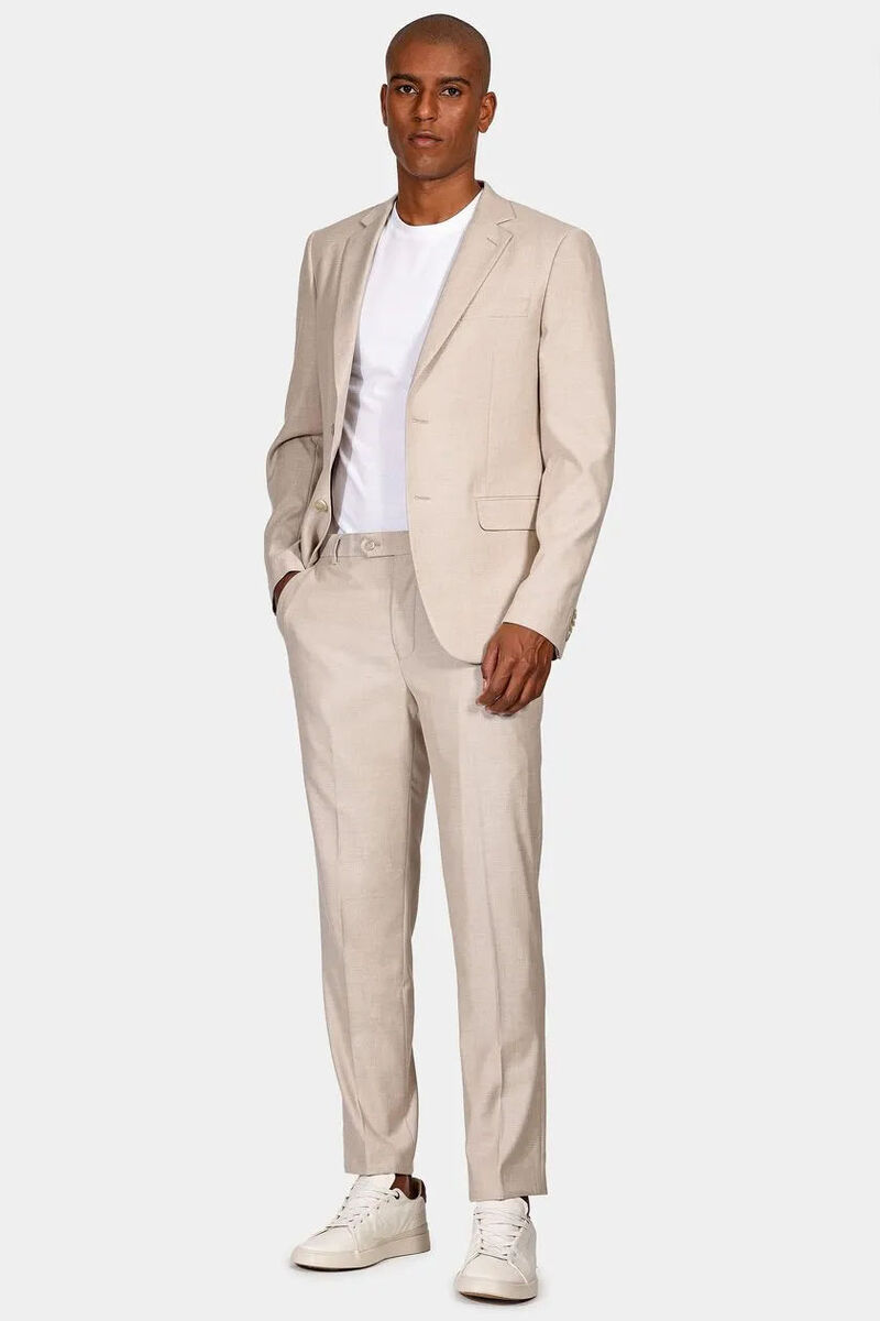 modelo usando um blazer e calça de alfaiataria na cor bege em um fundo branco 