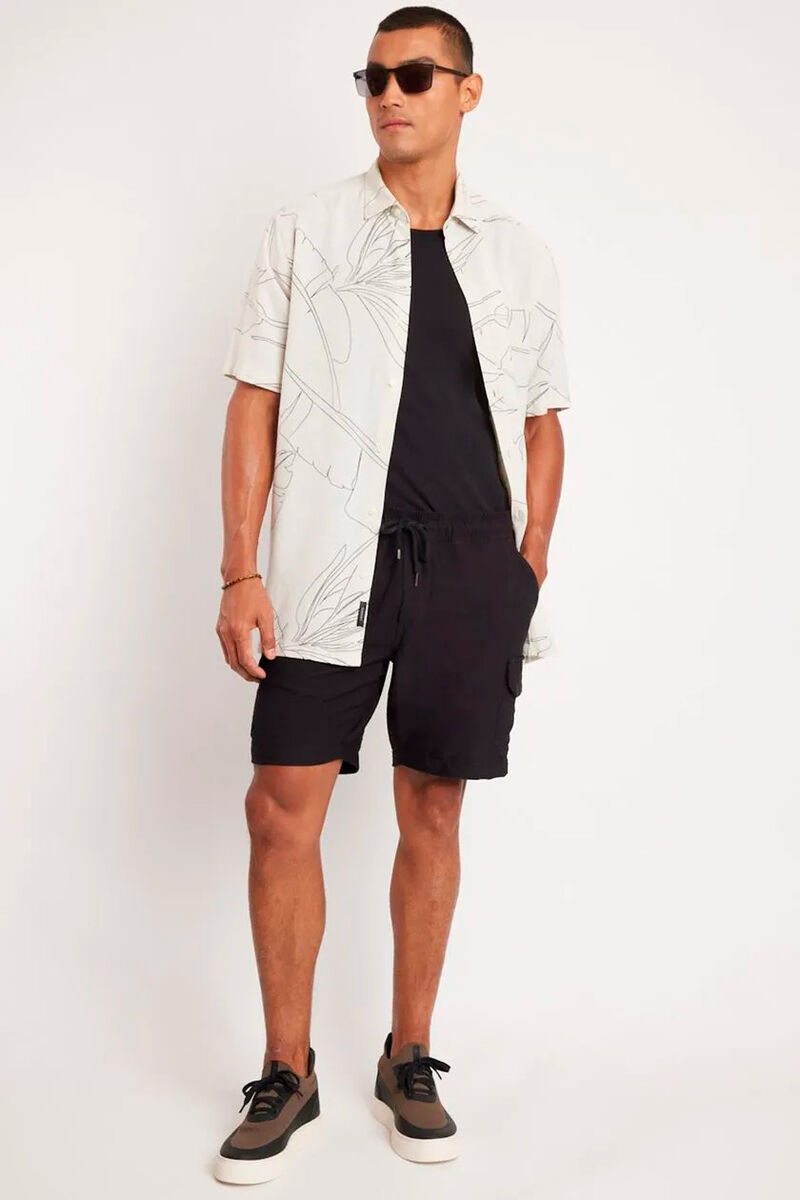 modelo usando uma bermuda preta, camiseta preta e uma camisa branca em um fundo branco