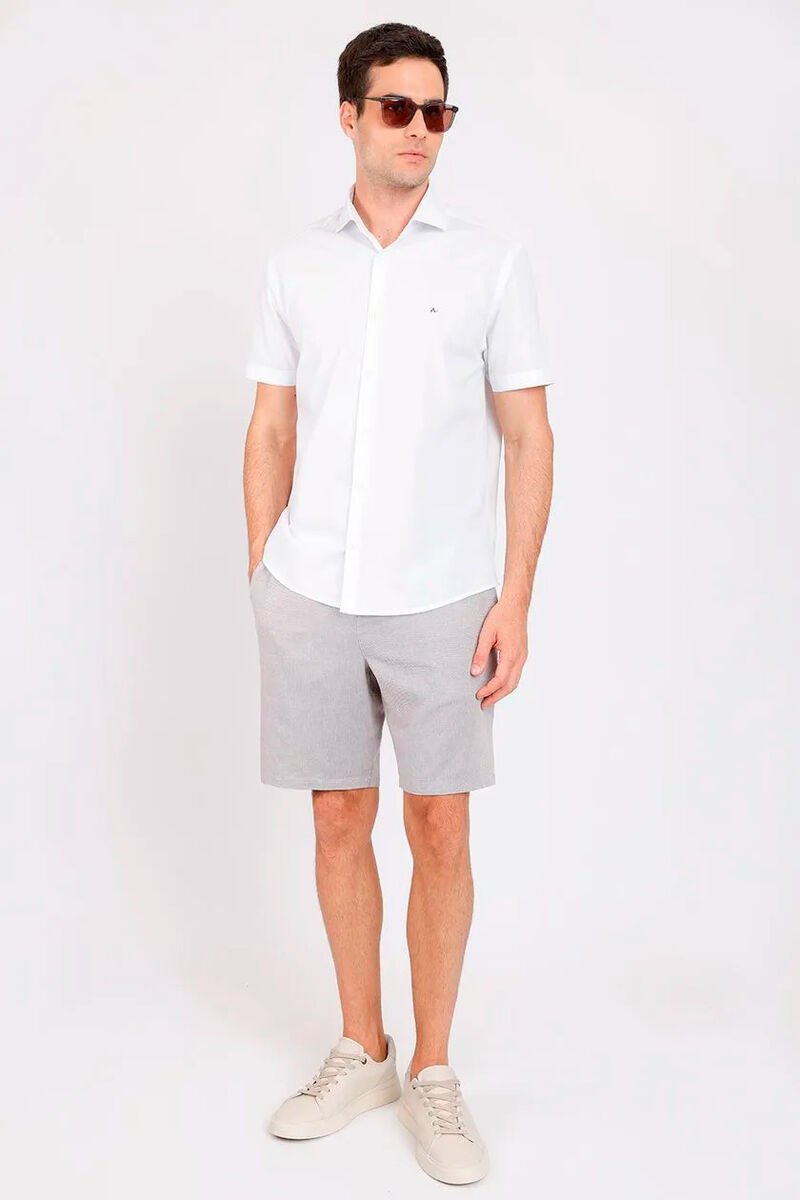 modelo usando uma bermuda chino caqui e uma camisa branca em um fundo branco