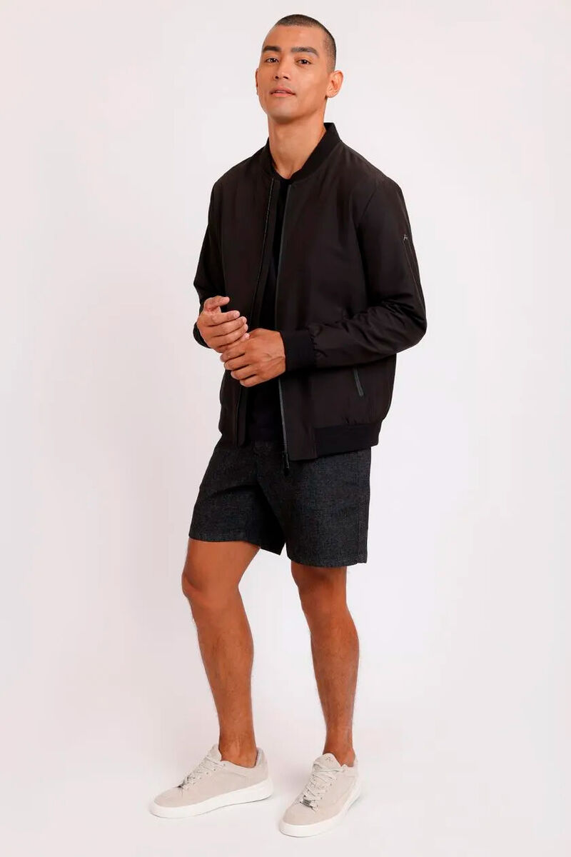 modelo usando uma camiseta preta e bermuda junto de uma jaqueta