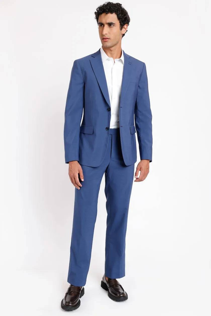 modelo com terno azul marinho e camisa branca por baixo em um fundo branco