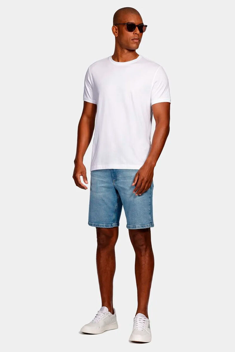 modelo usando uma camiseta branca com uma bermuda jeans em um fundo branco