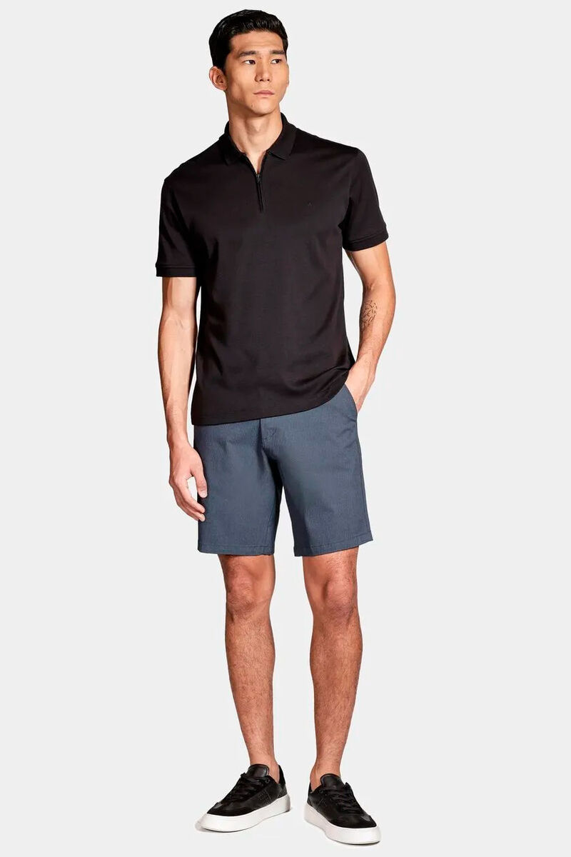 modelo usando uma bermuda azul-marinho e uma camiseta polo preta em um fundo branco