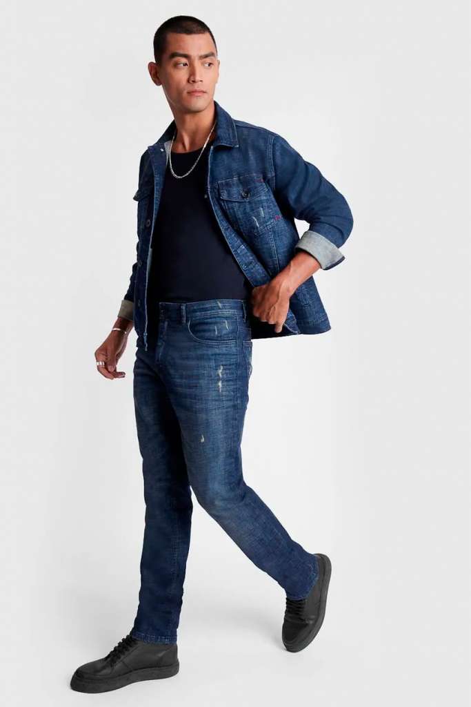 Homem em jeans e jaqueta denim posando em pé