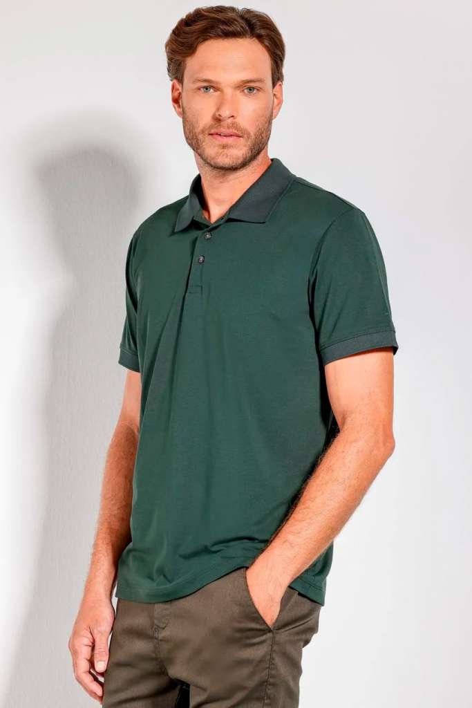 Homem usando uma polo verde em fundo neutro.