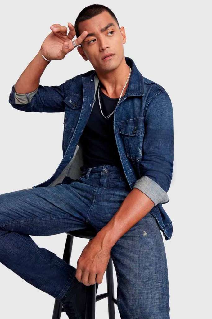 Homem posando com roupas jeans em fundo neutro