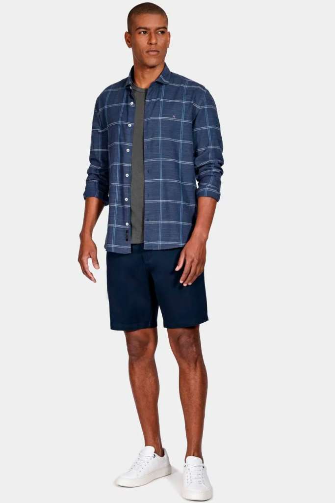 Homem posando com camisa xadrez e short de verão.
