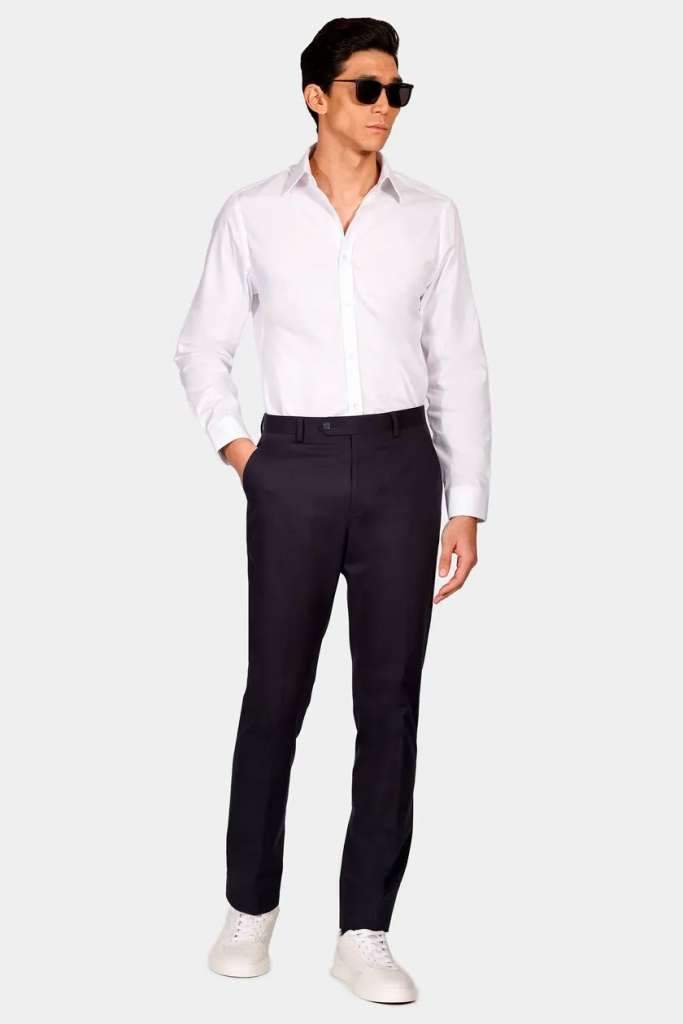 Homem elegante de camisa branca e calça escura.