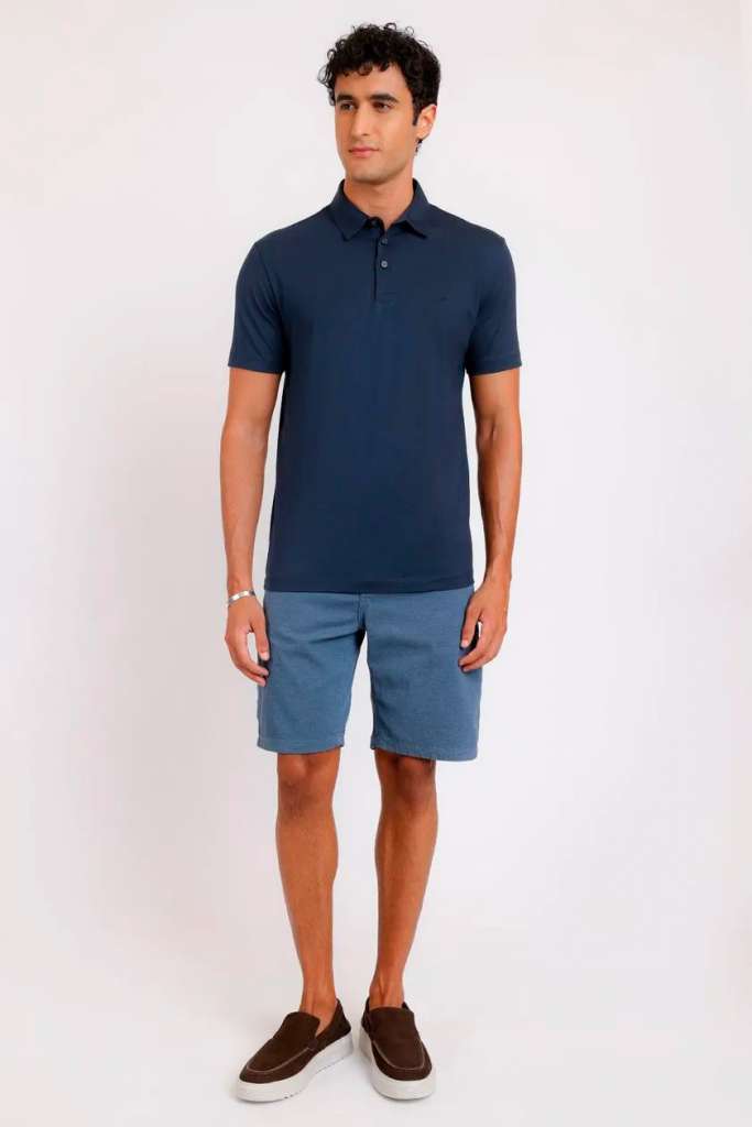 Homem usando polo azul e shorts, estilo casual.