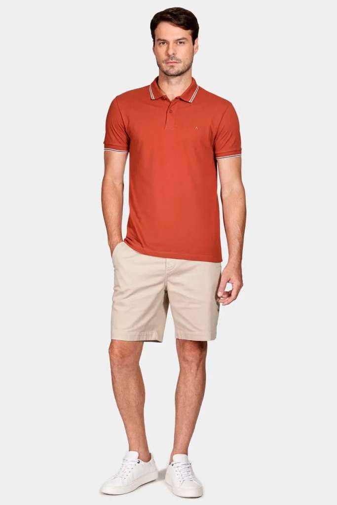 Homem vestindo polo laranja e shorts claros