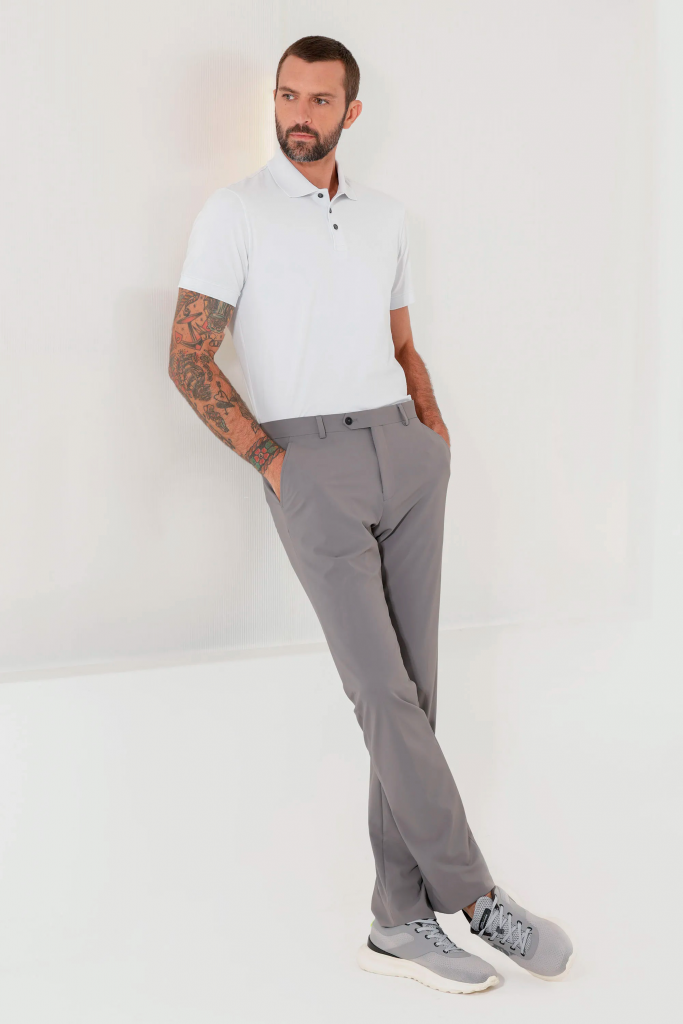 Homem estiloso usando camisa polo branca e calça cinza.