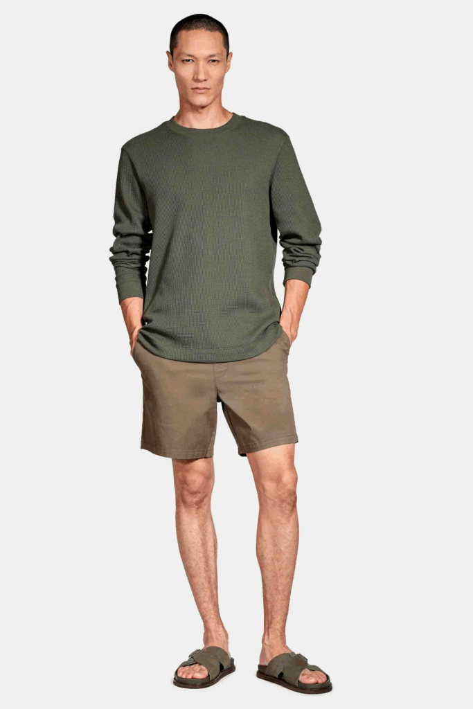 Homem em camiseta verde e shorts bege, posando.