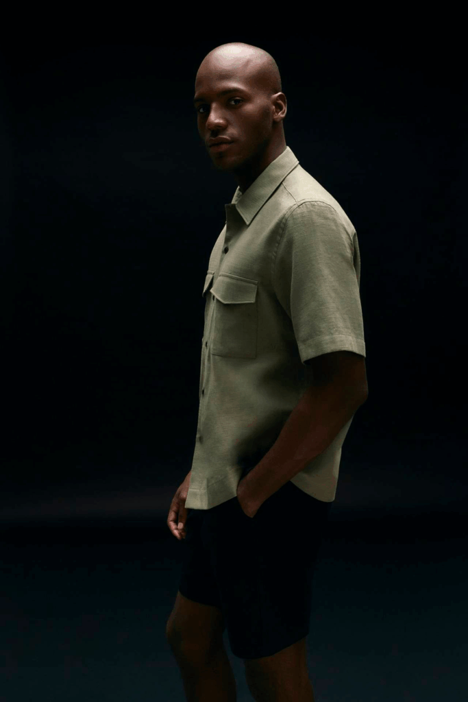 Modelo masculino com camisa verde em fundo escuro