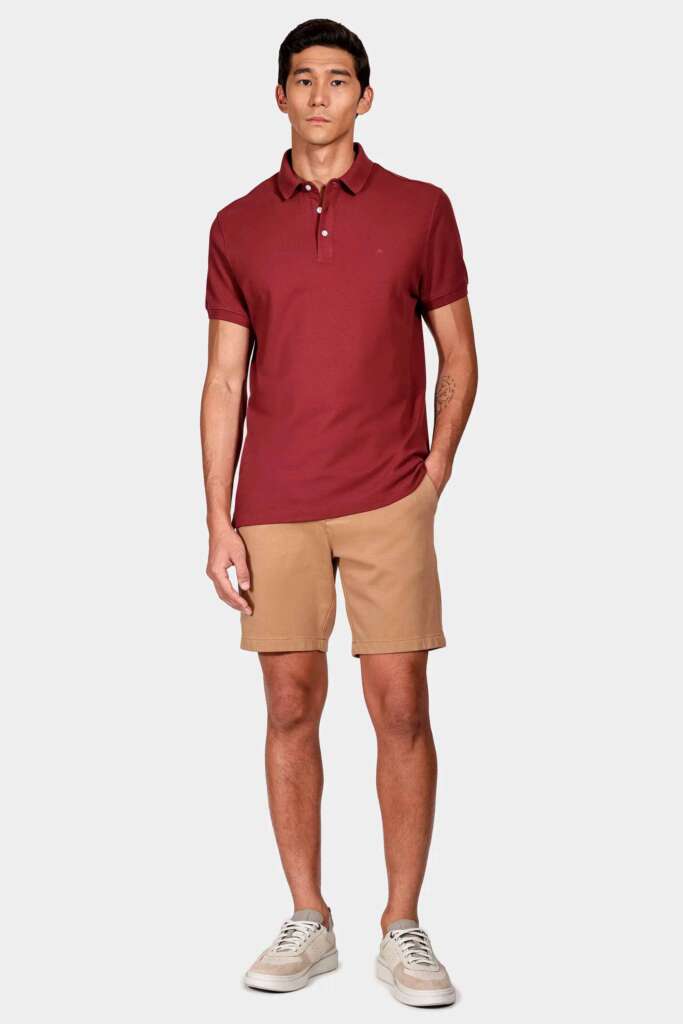 modelo masculino usando uma bermuda e camisa polo em um fundo branco 