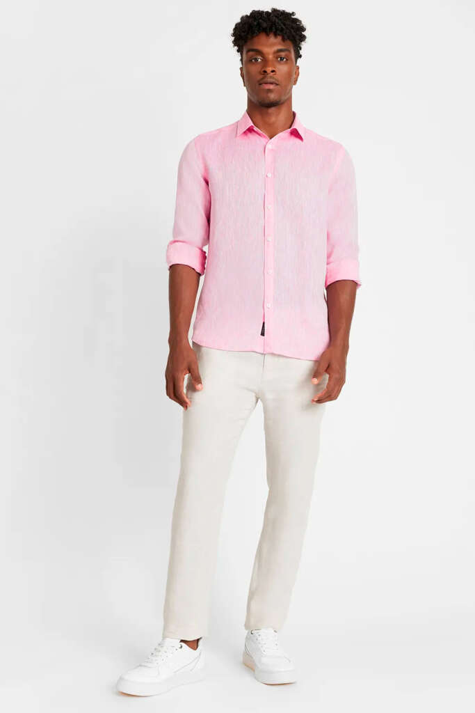 modelo masculino usando uma camisa de linho rosa e uma calça chino bege