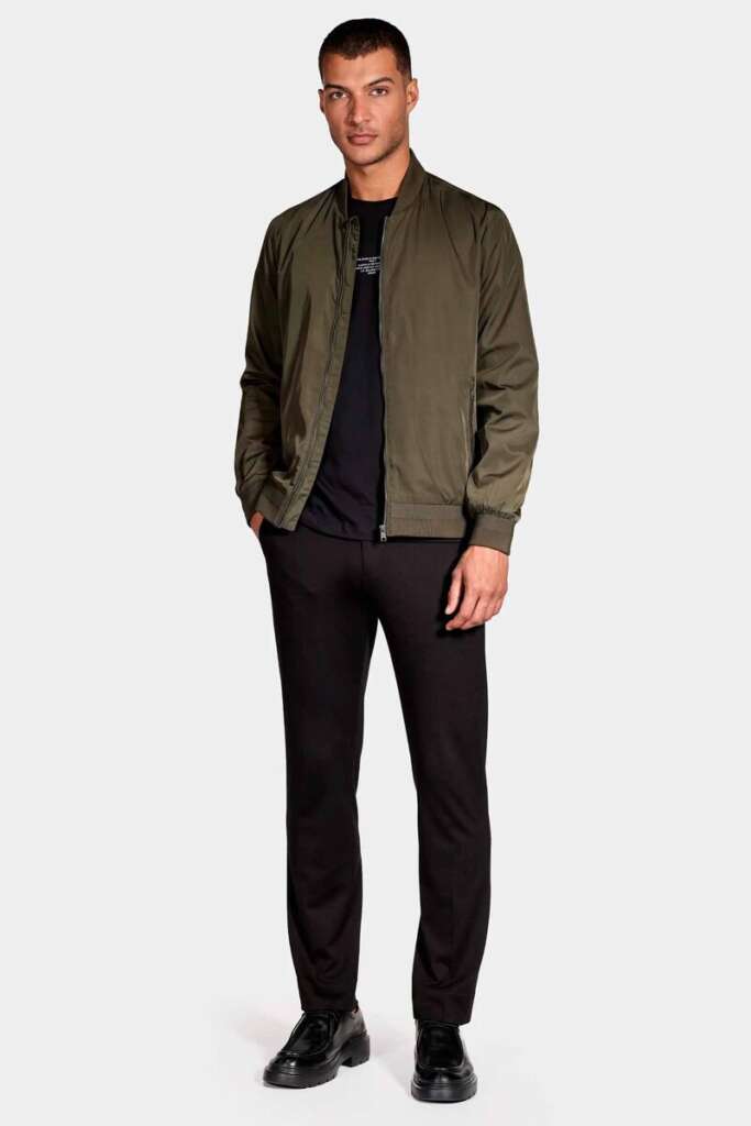 modelo masculino com uma camisa preta, calça preta e jaqueta de couro em um fundo branco 