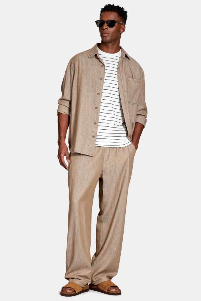 modelo masculino usando calça oversized e camisa branca em um fundo branco 