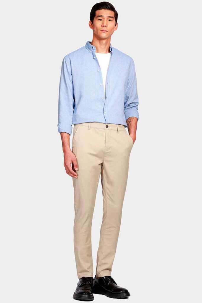 modelo masculino usando uma camisa azul claro e calça bege em um fundo branco 