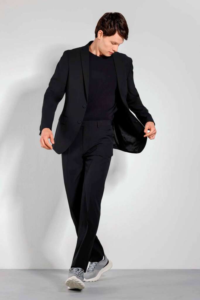 Homem em terno preto com tênis casual.