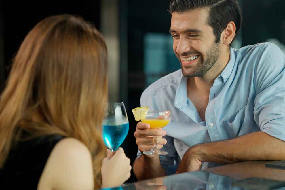 bar Casal brindando com drinks coloridos em bar