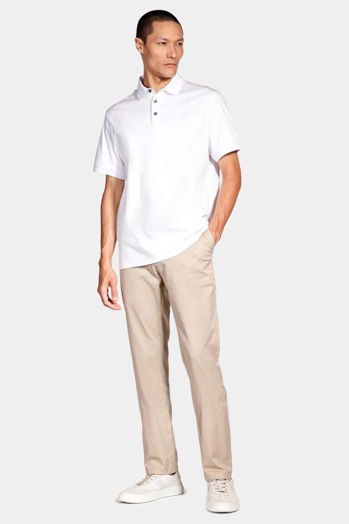 modelo masculino usando uma camisa polo branco e uma calça clara em um fundo claro 