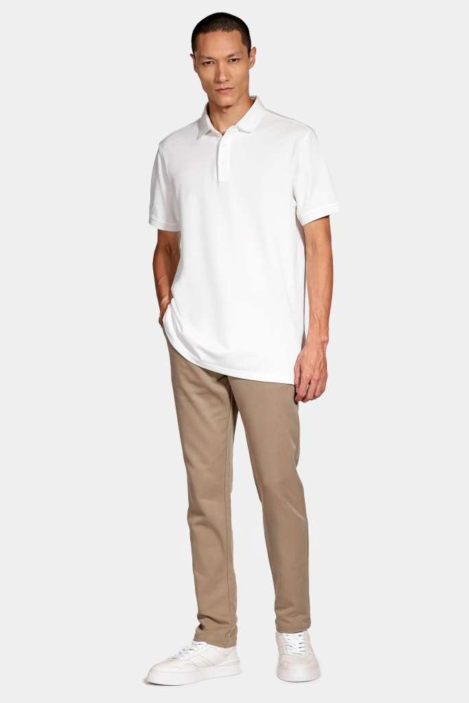 modelo masculino usando uma polo e uma calça alfaiataria em um fundo branco 