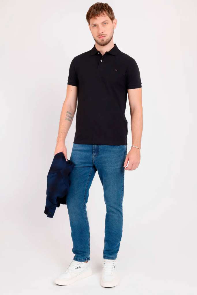 modelo masculino usando uma camiseta preta, uma calça jeans e segurando uma jaqueta em um fundo branco 