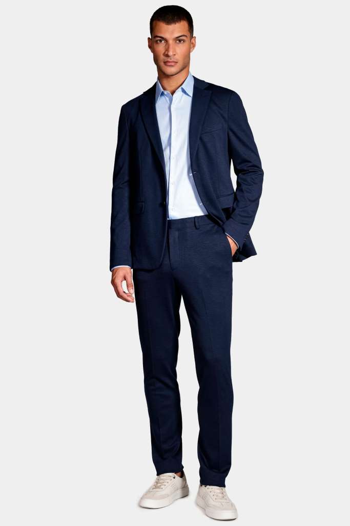 modelo masculino usando uma camisa azul claro junto de um terno azul escuro em um fundo branco 