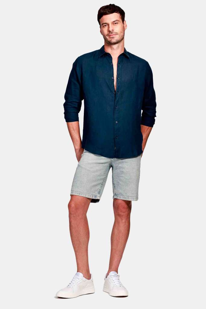 um modelo masculino usando uma camisa de linho preto e bermuda jeans em um fundo branco 