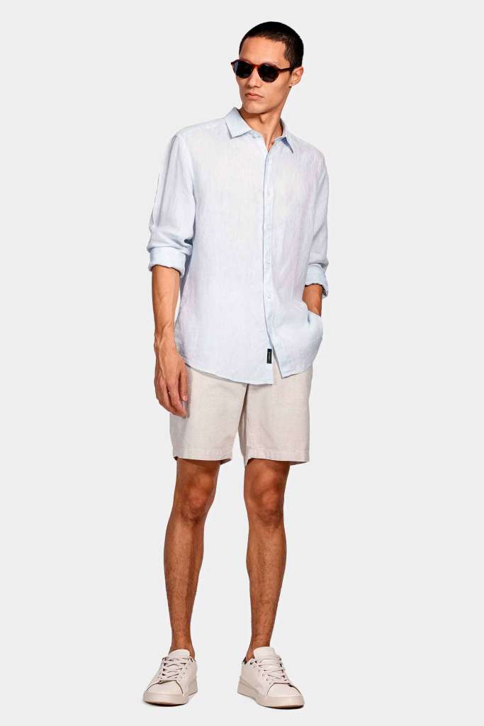 modelo masculino usando uma camisa azul claro e uma calça clara em um fundo branco 
