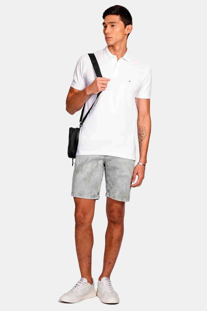 modelo masculino usando uma camisa polo branco e uma bermuda jeans em um fundo branco 