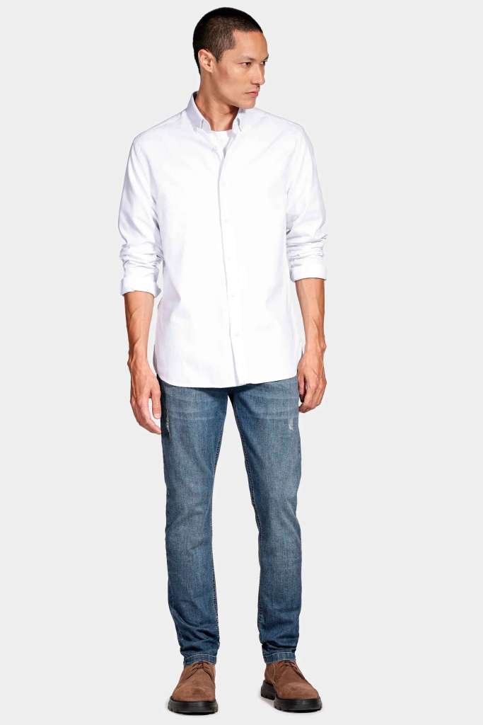 um modelo masculino usando uma camisa branca e uma calça jeans em um fundo branco
