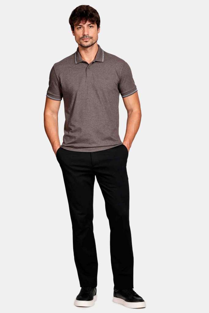 modelo masculino usando uma camisa polo, jeans escuro e tenis marrom em um fundo branco 